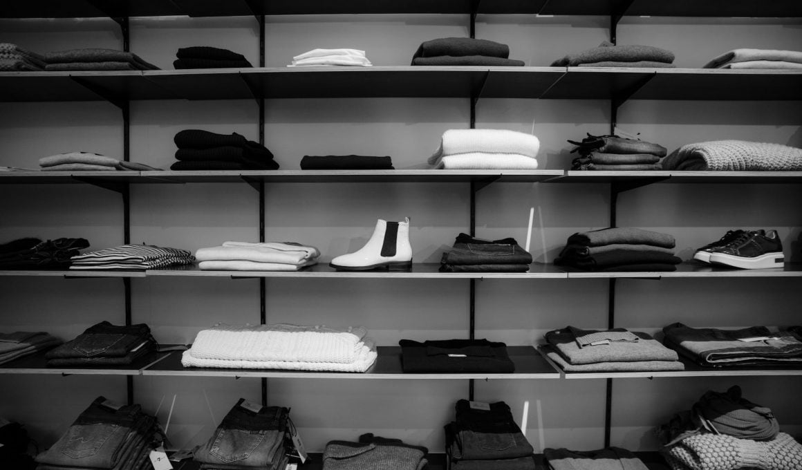 grayscale photography of assorted apparels on shelf rack