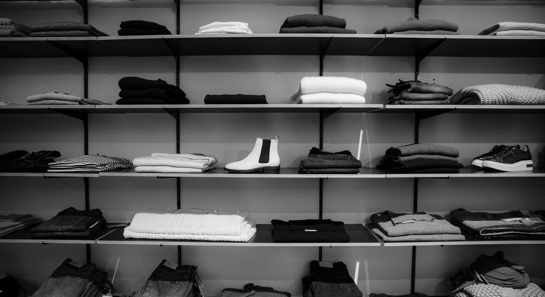 grayscale photography of assorted apparels on shelf rack