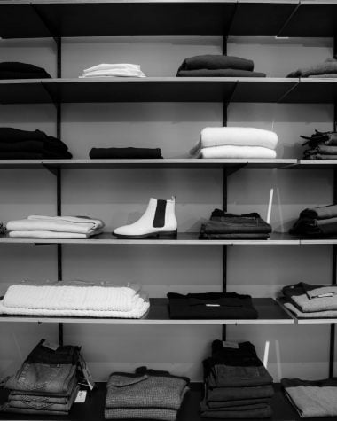 grayscale photography of assorted apparels on shelf rack