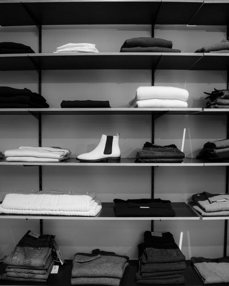 grayscale photography of assorted apparels on shelf rack